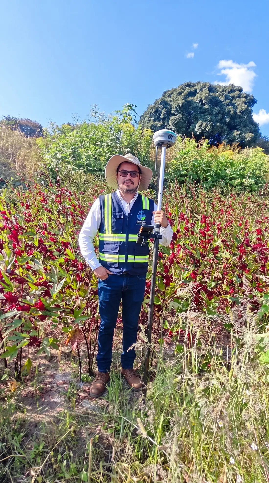 Integrante de la brigada con bastón GNSS en un cultivo